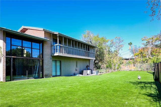 rear view of property with cooling unit, a lawn, and a balcony