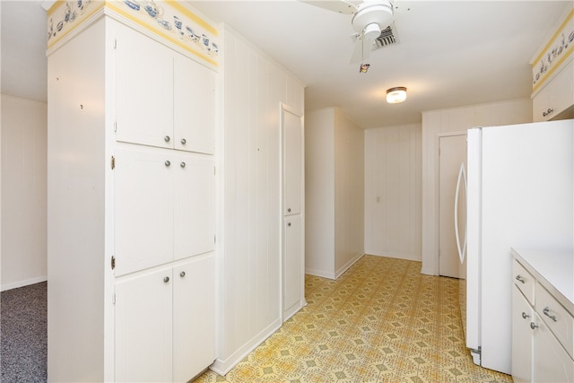 kitchen featuring white cabinets, wood walls, and white refrigerator