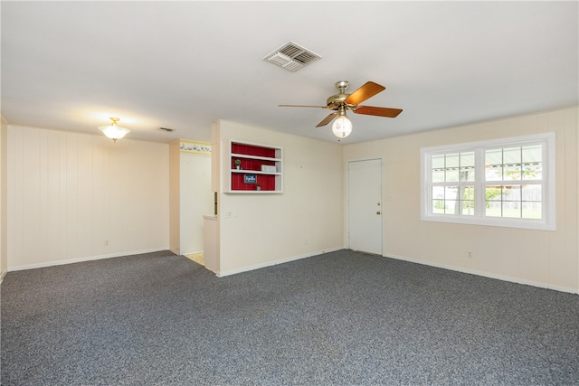 unfurnished room with ceiling fan and dark carpet