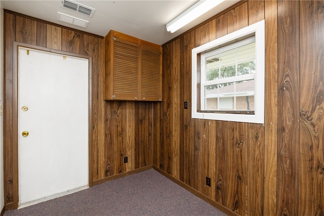 carpeted empty room with wooden walls