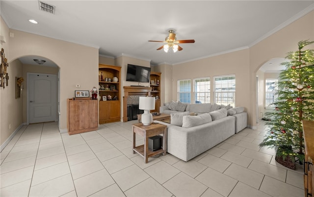 tiled living room with crown molding, built in shelves, and ceiling fan