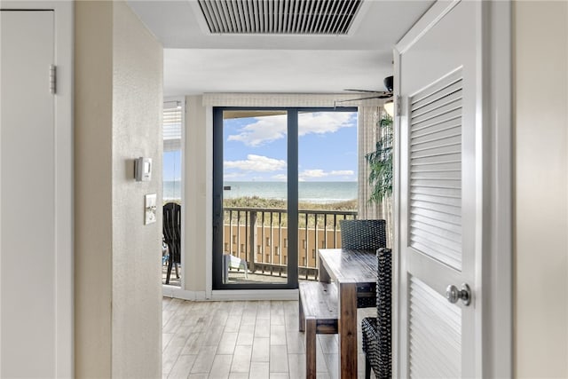 doorway with a view of the beach, a water view, and ceiling fan