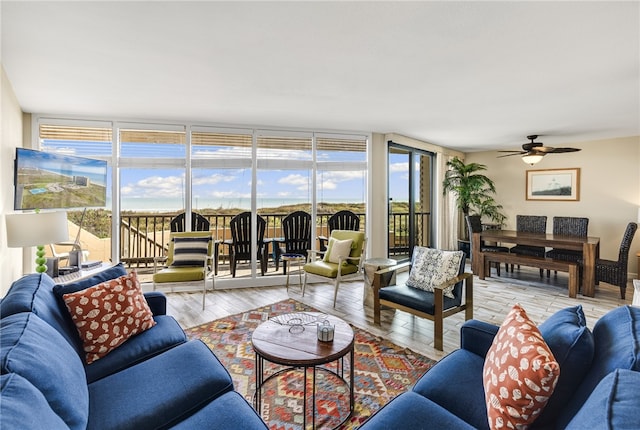 living room with light wood-type flooring, expansive windows, and ceiling fan