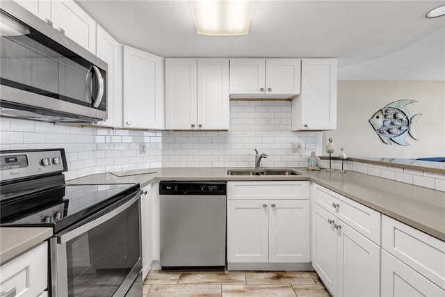 kitchen with sink, backsplash, white cabinets, and stainless steel appliances