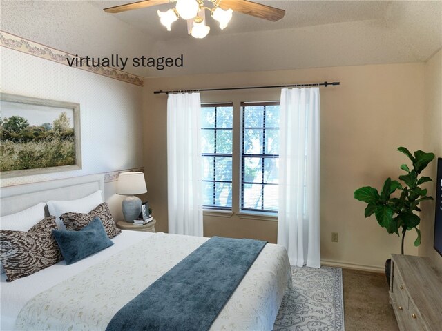 carpeted bedroom with lofted ceiling, wallpapered walls, ceiling fan, and baseboards