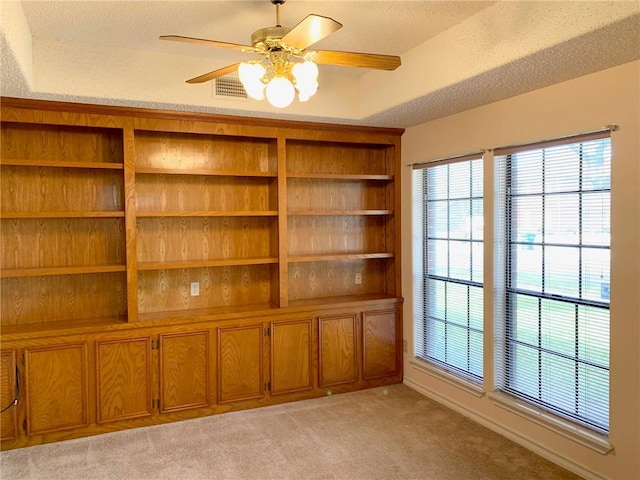 empty room featuring light carpet, ceiling fan, visible vents, and a textured ceiling