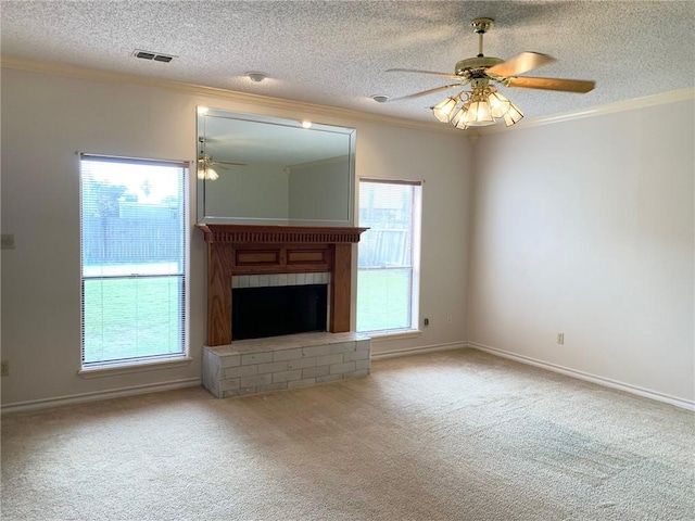 unfurnished living room with crown molding, a fireplace, visible vents, a ceiling fan, and carpet flooring