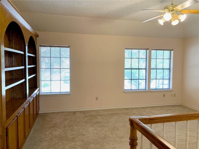 spare room with ceiling fan, a textured ceiling, and light carpet