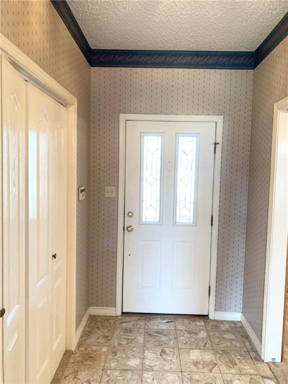 foyer entrance featuring a textured ceiling and ornamental molding