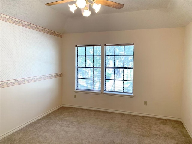 carpeted empty room featuring ceiling fan, plenty of natural light, and vaulted ceiling