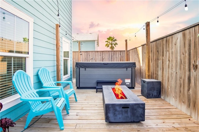 deck at dusk with an outdoor fire pit and a hot tub