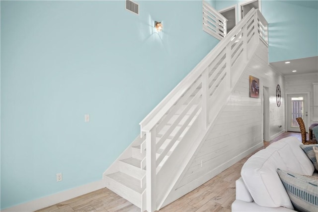 stairway with hardwood / wood-style floors and a high ceiling