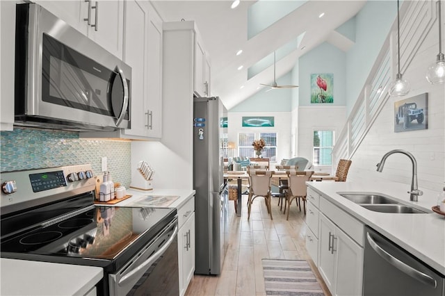 kitchen featuring sink, white cabinetry, tasteful backsplash, decorative light fixtures, and appliances with stainless steel finishes