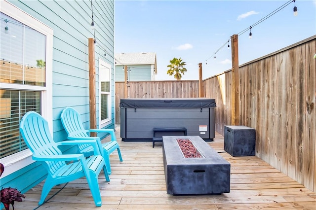 wooden deck with an outdoor fire pit and a hot tub