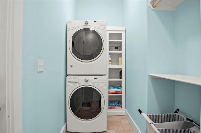 washroom with stacked washer / drying machine and light wood-type flooring