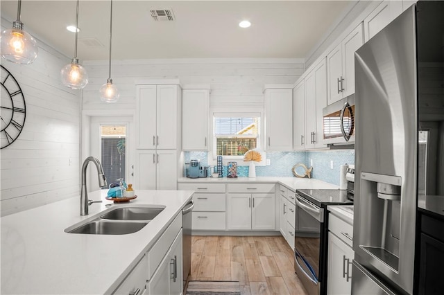 kitchen featuring pendant lighting, sink, white cabinetry, backsplash, and stainless steel appliances