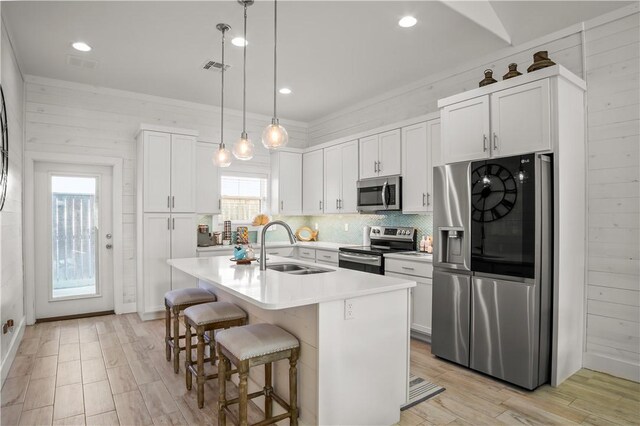 kitchen featuring sink, white cabinetry, hanging light fixtures, an island with sink, and stainless steel appliances