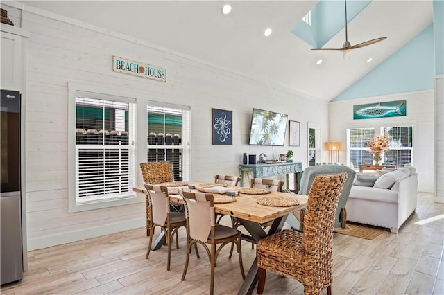 dining area with ceiling fan, a healthy amount of sunlight, high vaulted ceiling, and light hardwood / wood-style flooring