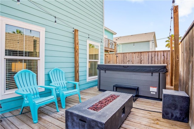 wooden terrace featuring an outdoor fire pit and a hot tub