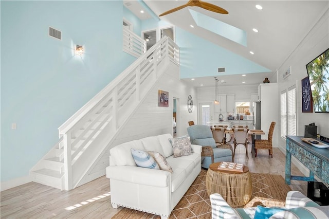 living room featuring light hardwood / wood-style flooring, high vaulted ceiling, and ceiling fan