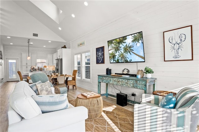 living room featuring sink, high vaulted ceiling, and light hardwood / wood-style flooring