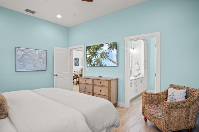 bedroom featuring connected bathroom and light hardwood / wood-style flooring