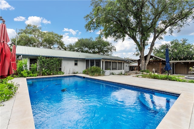 view of swimming pool with a sunroom and a patio area