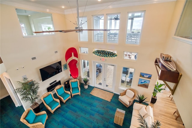 living room featuring a towering ceiling, hardwood / wood-style floors, crown molding, and french doors