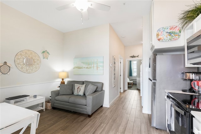 kitchen with stainless steel appliances, ceiling fan, and light hardwood / wood-style flooring