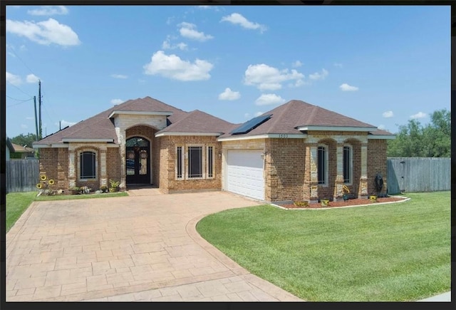 view of front facade with a garage, a front yard, and solar panels