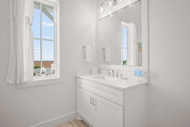 bathroom with wood finished floors, vanity, and baseboards