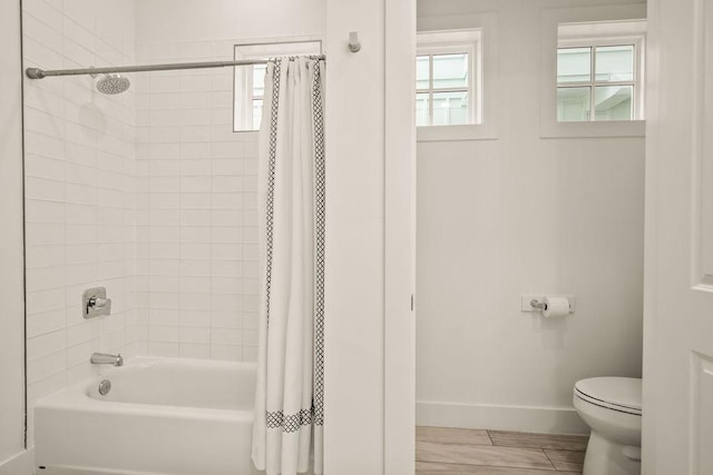 full bath with shower / tub combo, toilet, and baseboards