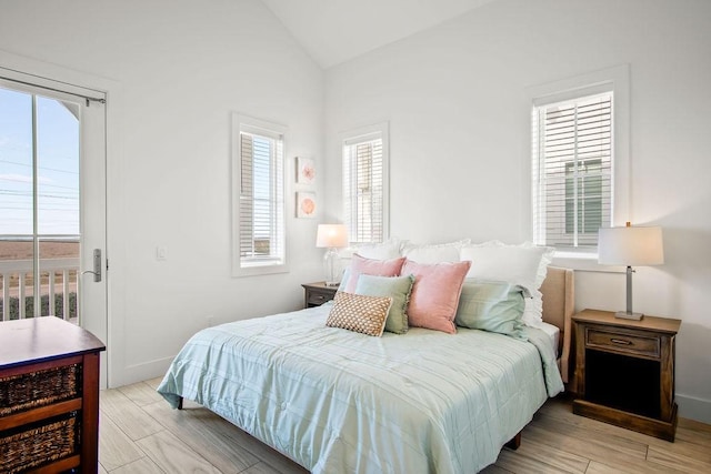 bedroom featuring lofted ceiling, light wood-type flooring, and baseboards