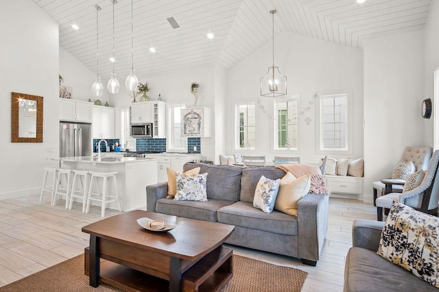 living room with high vaulted ceiling, wood ceiling, a notable chandelier, and light wood finished floors