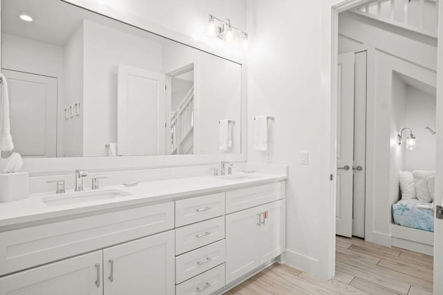 bathroom featuring double vanity, wood finished floors, a sink, and baseboards