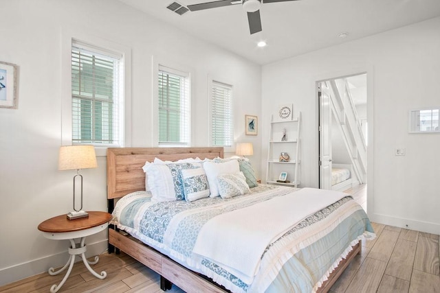 bedroom with baseboards, a ceiling fan, visible vents, and wood tiled floor