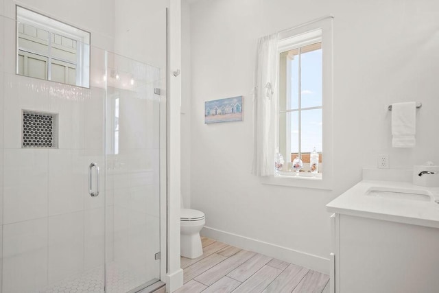 bathroom featuring a healthy amount of sunlight, a stall shower, baseboards, and toilet