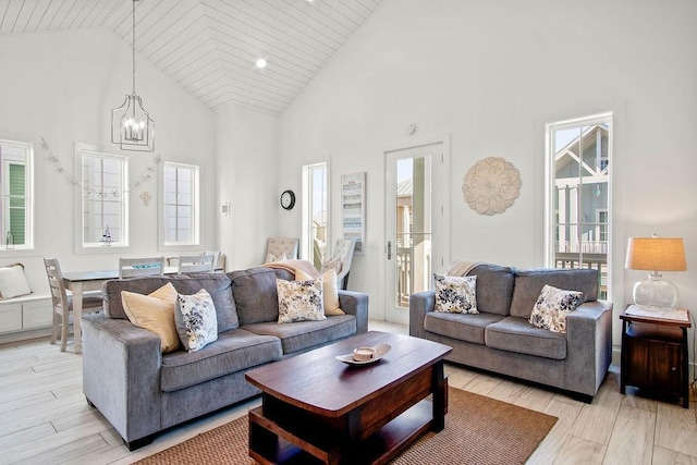 living room with a chandelier, high vaulted ceiling, and light wood finished floors