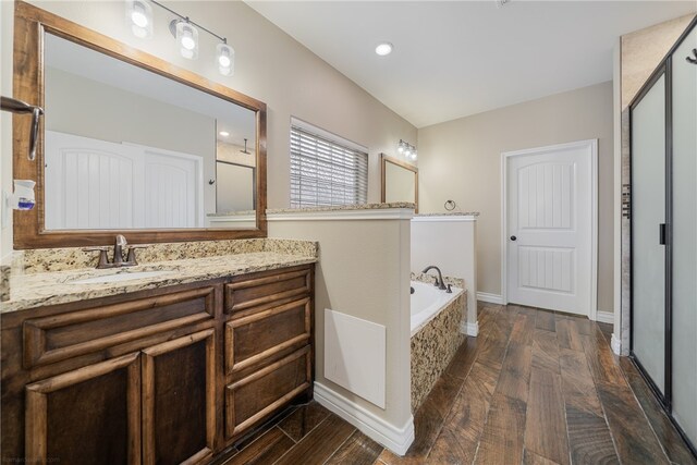 bathroom with vanity, hardwood / wood-style flooring, and plus walk in shower