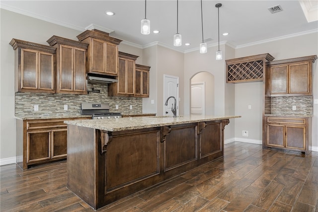 kitchen with dark hardwood / wood-style floors, stainless steel stove, a center island with sink, and pendant lighting