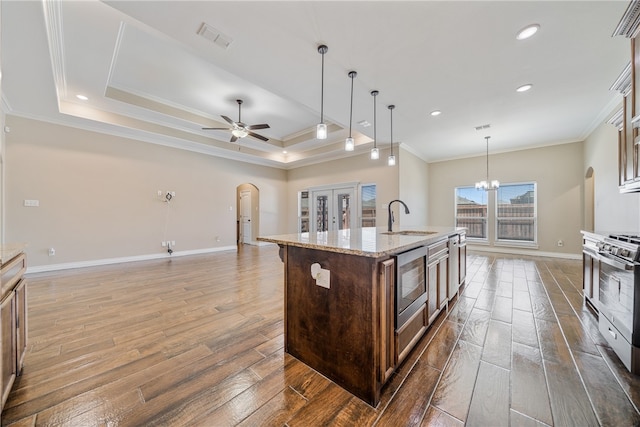 kitchen with ornamental molding, a center island with sink, appliances with stainless steel finishes, dark hardwood / wood-style flooring, and sink