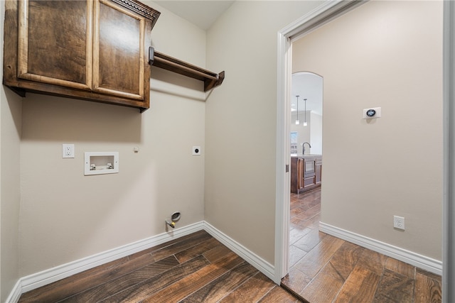 washroom featuring dark hardwood / wood-style flooring, electric dryer hookup, cabinets, gas dryer hookup, and washer hookup