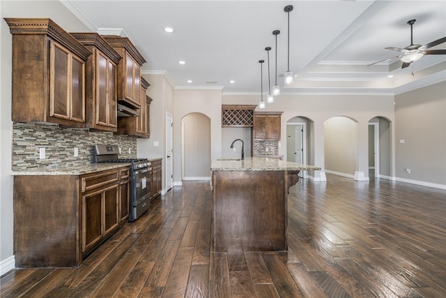 kitchen with an island with sink, stainless steel gas range, dark hardwood / wood-style floors, and pendant lighting