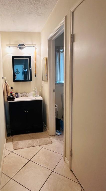 bathroom with a textured ceiling, toilet, vanity, and tile patterned flooring