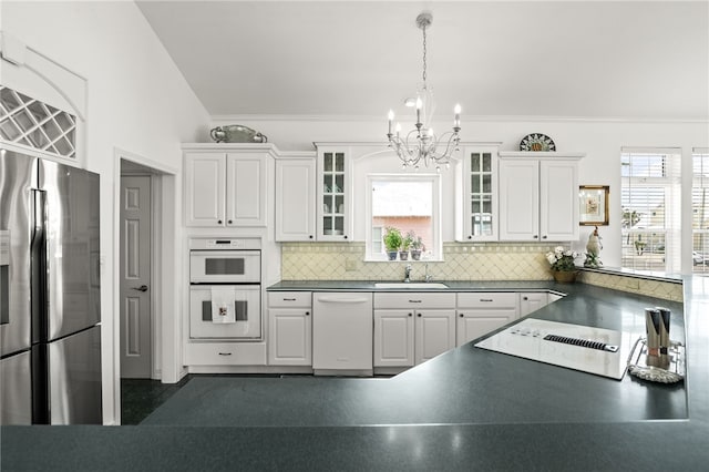 4820 Sanibel Ln, Port Aransas, TX 78373 - kitchen with a notable chandelier, tasteful backsplash, white appliances, dark countertops, and white cabinets