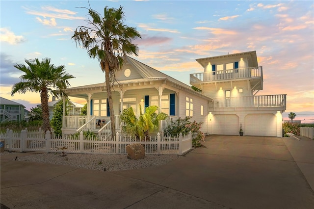 4820 Sanibel Ln, Port Aransas, TX 78373 - view of front facade with concrete driveway, a balcony, an attached garage, a porch, and a fenced front yard