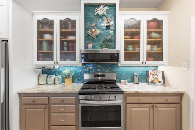 kitchen with gray cabinets, light stone countertops, decorative backsplash, and appliances with stainless steel finishes