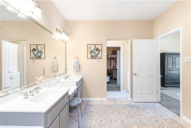 bathroom with tile patterned flooring, vanity, baseboards, and a spacious closet
