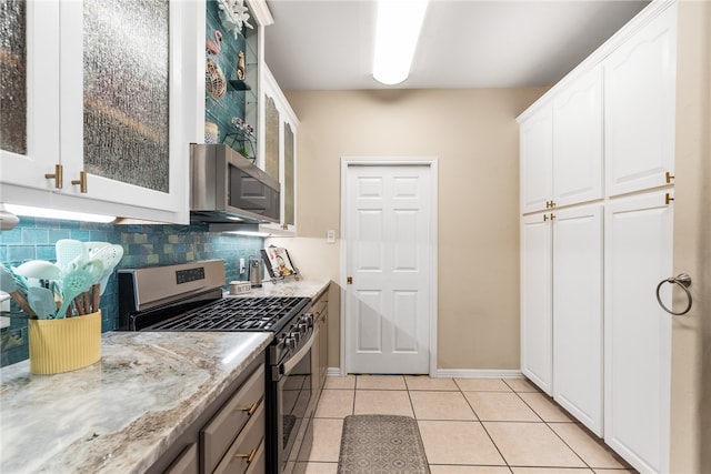 kitchen featuring tasteful backsplash, light tile patterned flooring, light stone countertops, white cabinetry, and appliances with stainless steel finishes