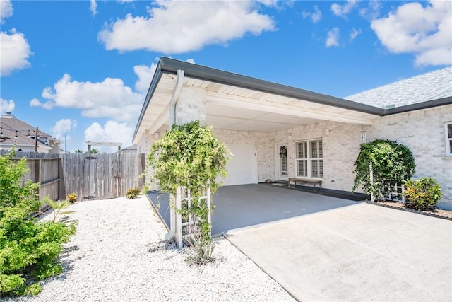 rear view of house with driveway, fence, and a carport